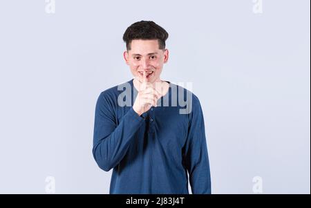 Mann gestikuliert ruhig bleiben, Guy lächelt mit Finger auf dem Mund zeigt Stille Geste, attraktive männliche Flüstern Stille Stockfoto