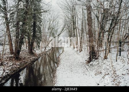 Ein kleiner Fluss in Leipzig in einem verschneiten Park ohne Menschen in Sicht. Stockfoto