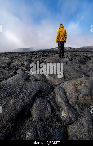 Tourist steht auf versteinerte Lava, vulkanischer Stein in bizarren Formen, Lavafeld, Vulkanausbruch, aktiver Tischvulkan Fagradalsfjall, Krysuvik Stockfoto