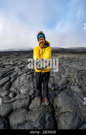 Tourist steht auf versteinerte Lava, hält Lavasteine in der Hand, vulkanischen Stein in bizarren Formen, Lavafeld, Vulkanausbruch, aktiver Tisch Stockfoto