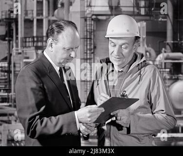 1960S ZWEI MÄNNER IN EINEM INDUSTRIESTANDORT ÜBERPRÜFEN DATEN AUF DER ZWISCHENABLAGE, EINER TRÄGT HARTE MÜTZE ARBEITSKLEIDUNG, DER ANDERE IN BUSINESS-ANZUG - I5651 HAR001 HARS STUDIO SHOT MANAGER COPY SPACE HALF-LENGTH PERSONEN MÄNNER BERUF MANAGEMENT FÜHRUNGSKRÄFTE MITTLEREN ALTERS S & W MITTLEREN ALTERS MANN DATEN SKILL ANZUG UND KRAWATTE BERUF FÄHIGKEITEN CHEMISCHER STANDORT KARRIERE ZUSAMMENGESETZTES WISSEN ARBEIT BESCHÄFTIGUNG BERUFE RAFFINERIE CHEFS VERBINDUNG ÜBERPRÜFUNG SUPPORT-INFRASTRUKTUR MITARBEITER ZUSAMMENARBEIT MANAGER MID-ADULT MID-ADULT MAN PETROLEUM SOLUTIONS SCHWARZ-WEISS KAUKASISCHE ETHNIE FOSSILE BRENNSTOFFE HAR001 ARBEIT ALTMODISCH Stockfoto