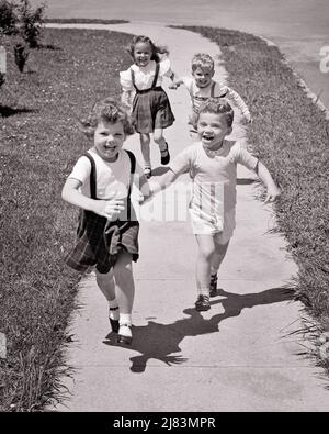 1950S VIER KINDER LAUFEN AUF DEM BÜRGERSTEIG IN DIE NÄHE DER KAMERA, ZWEI JUNGE UND JUNGE PAARE HALTEN DIE HÄNDE LÄCHELND LACHEND - J3967 HAR001 HARS BRUDER ALTE MODE SCHWESTER FITNESS JUGENDLICH GESICHTS LACHEN GESUNDE FREUND TEAMWORK WETTBEWERB ERFREUT FREUDE LIFESTYLE GESCHWINDIGKEIT FRAUEN BRÜDER GESUNDHEIT FREUNDSCHAFT GANZKÖRPERKONDITION PERSONEN MÄNNER GESCHWISTER VERTRAUEN GEGENÜBER SCHWESTERN AUSDRÜCKE B&W AUGENKONTAKT FREIHEIT AKTIVITÄT GLÜCK KÖRPERLICHE WELLNESS FRÖHLICHE KRAFT UND AUFREGUNG ERHOLUNG STOLZ HÄNDE AUF GESCHWISTERLÄCHELN KONZEPTIONELLE FLEXIBILITÄT FREUNDLICH FREUDIGE MUSKELN STILVOLL Stockfoto