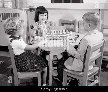 1950S DREI KINDER, ZWEI MÄDCHEN UND EIN JUNGE IN DER SONNTAGSSCHULE, DIE MIT EINER SPIELZEUGVERSION VON NOAH’S ARCHE A SPIELEN JUNGE UND ZWEI MÄDCHEN - J7638 HAR001 HARS GLÜCK HIGH-ANGLE-ABENTEUER RELIGIÖSE UND CHRISTENHEIT WISSEN MÄCHTIG GENESIS FLUCHT TREU KOOPERATION GLAUBE WACHSTUM GEISTIGE ZWEISAMKEIT ARK GLAUBE SCHWARZ-WEISS KAUKASISCHE ETHNIE HAR001 HEBRÄISCH INSPIRIERENDE JÜDISCHE JÜDISCHE JUDAISMUS ALTMODISCH OLD TESTAMENT SONNTAG SCHULVERSION Stockfoto