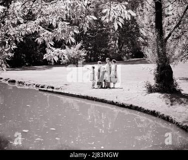 1950S FAMILIE VON 6 STEHEND AM TEICH IM PARK MIT PICKNICKKÖRBEN THERMOSKANNEN MUTTER VATER 4 KINDER EIN MÄDCHEN ZEIGT ZUR ANSICHT - J8077 HAR001 HARS IM FREIEN TRAGEND MANN PAPA BÄUME MAHLZEIT MAMA KLEIDUNG NOSTALGISCH AKTIV PAAR 4 VERLÄSST VORSTADT MÜTTER ALTE ZEIT NOSTALGIE BRUDER ALTE MODE SCHWESTER 1 JUGENDLICH STIL TEICH SÖHNE FAMILIEN FREUDE LIFESTYLE ZUFRIEDENHEIT FRAUEN VERHEIRATET BRÜDER EHEPARTNER EHEMÄNNER GESUNDHEIT HEIM LEBEN 6 NATUR KOPIEREN RAUM FREUNDSCHAFT GANZZAHL DAMEN TÖCHTER PERSONEN SZENISCHE INSPIRATION MÄNNER GESCHWISTER SCHWESTERN VÄTER S&W PARTNER SOMMERAKTIVITÄTEN GLÜCK ABENTEUER FREIZEIT Stockfoto