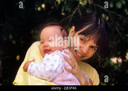 1990S BRÜNETTE MUTTER IN GELBEM OBERTEIL UMARMT IHRE KLEINE TOCHTER LÄCHELND IN ROSA UND WEISSEM OUTFIT - KB28337 NET002 HARS NOSTALGIE ALTE MODE 1 JUVENILE NIEDLICH SICHERHEIT JUNGE ERWACHSENE KLEINKIND STARKE FAMILIEN FREUDE LIFESTYLE FRAUEN ERWACHSEN GESUNDHEIT ZU HAUSE LEBEN KOPIE RAUM UMARMUNG DAMEN TÖCHTER PERSONEN FÜRSORGLICHE ALLEINERZIEHENDE KOMFORT ALLEINERZIEHENDE GLÜCK KOPF UND SCHULTERN BEQUEM UND STOLZ WEIBLICHE MENSCHEN BABYS LIEBEVOLLE NAHAUFNAHME MUTTERSCHAFT PERSÖNLICHE BINDUNG ZUNEIGUNG EMOTION WACHSTUM JUGENDLICHE MÜTTER SICHERE ZWEISAMKEIT JUNGE ERWACHSENE FRAU BABY MÄDCHEN KAUKASISCHE ETHNIE ALTMODISCH Stockfoto