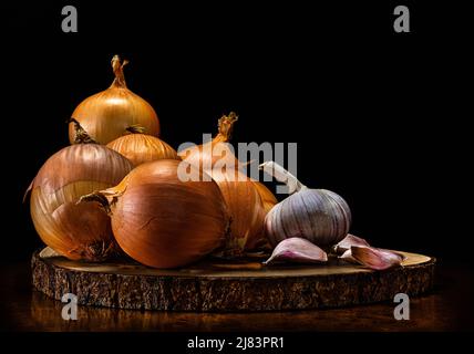 Zwiebeln und Knoblauch auf einem Holzständer. Zwiebeln- und Knoblauchgerichte helfen, Bakterien, Pilze und Viren effektiv zu beseitigen und viele Infektionskrankheiten zu verhindern. Stockfoto