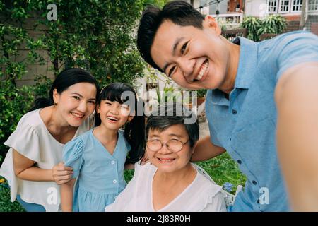 Eine Gruppe von asiatischen Familien mit mehreren Generationen, die gemeinsam im Garten ein Selfie-Foto machen und vor Glück lächeln. Familie verbringt Zeit und Liebe Konzept Stockfoto