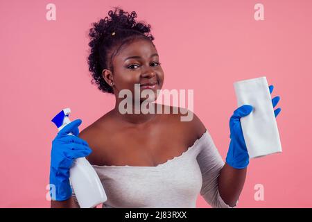 Frau mit Spray zu rosafarbenen Wänden backgroung Studio wischen Stockfoto