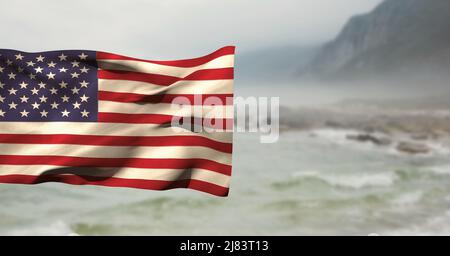 Zusammengesetztes Bild der wehenden amerikanischen Flagge gegen Landschaft mit Meer und Bergen Stockfoto