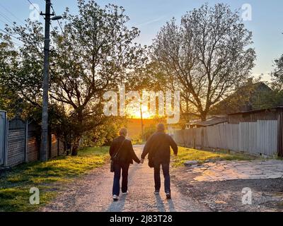 Dnipro, Dnipro, Ukraine. 12.. Mai 2022. Ein älteres ukrainisches Paar geht während des Sonnenuntergangs, inmitten der andauernden russischen Invasion in der Ukraine, mit Händen in ein Dorf in Dnipro. (Bild: © Daniel Ceng Shou-Yi/ZUMA Press Wire) Stockfoto