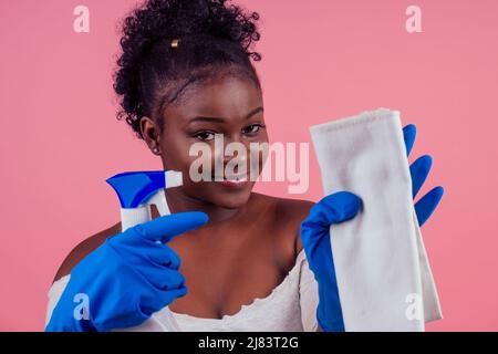 Frau mit Spray zu rosafarbenen Wänden backgroung Studio wischen Stockfoto