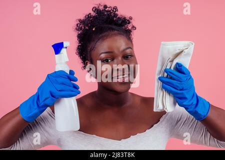 Frau mit Spray zu rosafarbenen Wänden backgroung Studio wischen Stockfoto