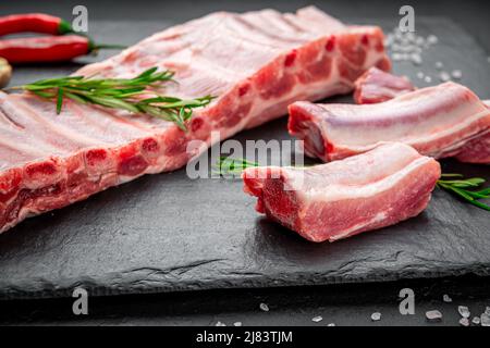Rohe Schweinefleischrippen auf einem steinernen Hintergrund. Frisches Schweinefleisch Stockfoto
