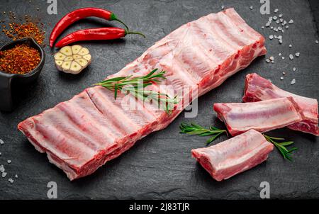 Rohe Schweinefleischrippen auf einem steinernen Hintergrund. Frisches Schweinefleisch Stockfoto