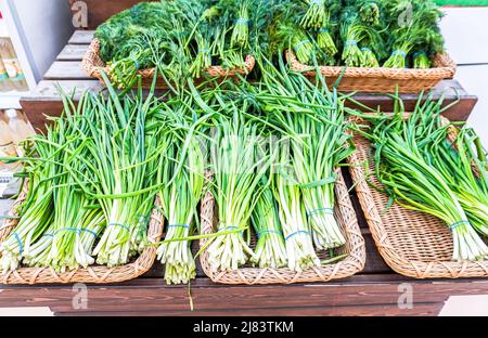Frische grüne Zwiebeln und andere grüne Kräuter werden im Lebensmittelgeschäft verkauft. Frisches grünes Gemüse auf den Märkten Stockfoto