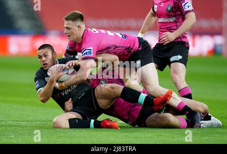 Die Tuimoala Lolohea von Huddersfield Giants wurde von Iain Thornley (Mitte) von Wigan Warriors und Sam Halsall während des Matches der Betfred Super League im John Smith's Stadium, Huddersfield, angegangen. Bilddatum: Donnerstag, 1212. Mai 2022. Stockfoto