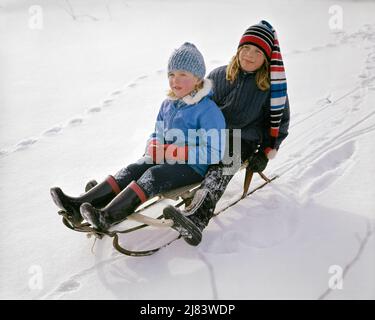 1960S ZWEI MÄDCHEN ROSIGEN WANGEN SCHWESTERN REITEN BLICK AUF SCHLITTEN ZUSAMMEN IM WINTERSCHNEE TRAGEN STRICKMÜTZEN JACKEN STIEFEL UND HANDSCHUHE - KW2816 HAR001 HARS GESUNDE TEAMARBEIT FAMILIEN FREUDE LIFESTYLE GESCHWINDIGKEIT FRAUEN LÄNDLICHEN SCHLITTEN GESUNDHEIT SCHLITTEN NACH HAUSE LEBEN KOPIE RAUM FREUNDSCHAFT GANZLÄNGE GESCHWISTER SCHWESTERN TRANSPORT STRICK WINTERZEIT AKTIVITÄT GLÜCK KÖRPERLICHE HOCHWINKEL ABENTEUER STÄRKE AUFREGUNG ERHOLUNG AUF BIS GESCHWISTER FLEXIBILITÄT MUSKELN ROSIG WINTERLICH ZUSAMMENARBEIT JUGENDLICHE PRE-TEEN PRE-TEEN MÄDCHEN ZWEISAMKEIT KAUKASISCHE ETHNIZITÄT HAR001 JACKEN ALTMODISCH Stockfoto