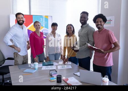 Porträt glücklicher, multirassischer Fachleute, die während der Besprechung im Büro im Sitzungssaal zusammenstehen Stockfoto
