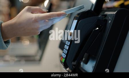 Details weibliche Hände zahlen mit Telefon Kauf per Handy elektronische Zahlungsmaschine Kartenleser E-Geld-Konzept. Kundin bezahlt Smartphone. Pos. Stockfoto