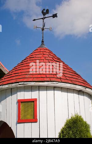 Weißer Holzplankenturm mit rotem Zedernholz-Schindeldach und Hahn-förmiges Weathervane. Stockfoto