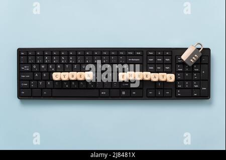 Konzeptuelles Bild von Online-Kriminalität - Computertastatur mit Holzwürfeln, die Cyber-Bedrohungen buchstabieren. Stockfoto