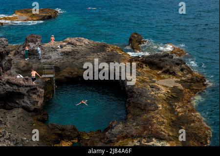 Teneriffa, Spanien. 12.. Mai 2022. Touristen und Einheimische genießen das Schwimmen und Sonnenbaden in einem natürlichen Salzwasserpool, der sich in einem Gebiet mit vulkanischen Klippen in der Nähe der Stadt Los Abrigos befindet. Während der Woche werden auf den Kanarischen Inseln hohe Temperaturen registriert. Quelle: Marcos del Mazo/Alamy Live News Stockfoto