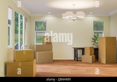 Mehrere Kartons, Stuhl und Pflanze auf dem Boden des leeren Raumes des Hauses mit leerer Wand. Stockfoto