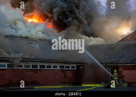 Hannover, Deutschland. 12.. Mai 2022. Eine Turnhalle der Schillerschule im Stadtteil Kleefeld ist in Flammen. Großalarm für die Feuerwehr Hannover: Aus noch ungeklärter Ursache ist in zwei Turnhallen einer Schule im Landkreis Kleefeld ein Brand ausgebrochen. Es gab zunächst keine Hinweise auf Verletzte. Quelle: Moritz Frankenberg/dpa/Alamy Live News Stockfoto