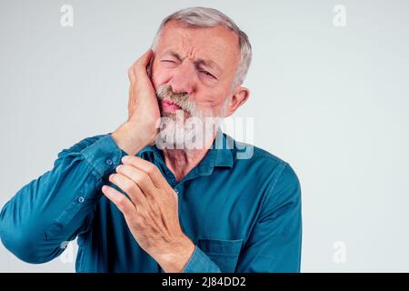 Unglücklicher älterer Mann mit geschlossenen Augen, die die Wange isoliert vor weißem Hintergrund halten, starke Schmerzen bei Karies Stockfoto