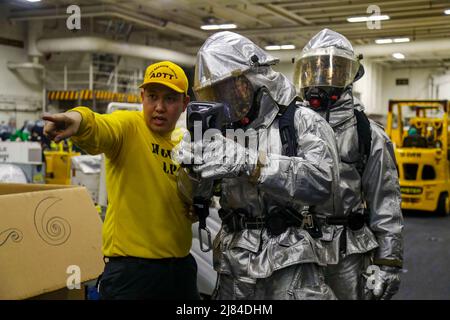 Apr 30, 2022 - Philippine Sea - Aviation Boatswain Mate (Handling) 1. Class Dionisio Caguioa, links, aus Dededo, Guam, instruiert Aviation Boatswain Mate (Handling) 3. Class Taylor Rams, Mitte, aus Wichita Falls, Texas, Und Aviation Boatswain Mate (Handling) Airman Anthony DeLoach aus Jacksonville, Florida, auf der Suche nach Verletzten während einer allgemeinen Quartiersübung an Bord des Flugzeugträgers USS Abraham Lincoln (CVN 72) der Nimitz-Klasse. Die Abraham Lincoln Strike Group befindet sich im geplanten Einsatzbereich der US-Flotte für 7., um die Interoperabilität durch Allianzen und Partner zu verbessern Stockfoto