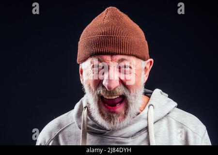 Porträt von traurigen alten älteren männlichen Tramp trägt warmen braunen Hut und undichte Handschuhe, hält Metall-Dose Bank Glas für Geld Almosen im Studio schwarzen Hintergrund Stockfoto