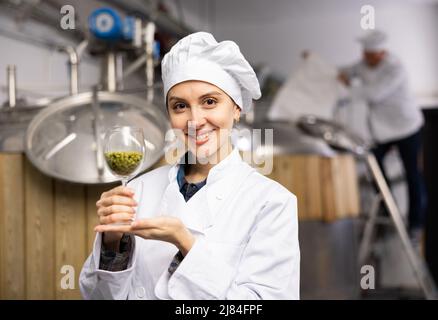 Porträt einer Braumeisterin, die ein Glas Hopfenpellets hält Stockfoto