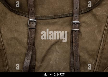 Nahaufnahme Textur eines Rucksack aus Canvas-Stoff. Lederriemen und Metallschnallen. Vintage Khaki Hintergrund. Stockfoto