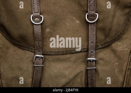 Nahaufnahme Textur eines Rucksack aus Canvas-Stoff. Lederriemen und Metallschnallen. Vintage Khaki Hintergrund. Stockfoto