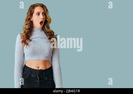 Porträt einer jungen schockierten Frau mit langen lockigen Haaren Studio Stockfoto