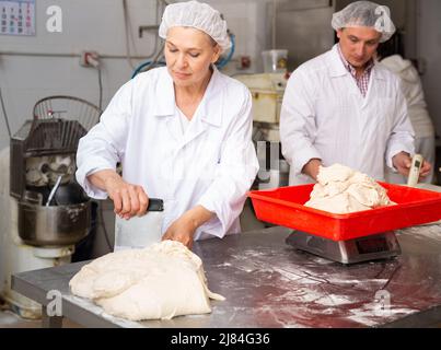 Bäcker wiegen den Teig auf der Waage Stockfoto
