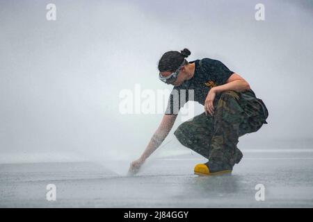 Pazifischer Ozean. 10.. Mai 2022. Damage Controlman 3. Klasse Rheann Hietpas aus Kaukauna, Wisconsin, inspiziert einen Gegenmassewäschungsregner auf dem Flugdeck des einzigen vorwärts eingesetzten Flugzeugträgers der US Navy USS Ronald Reagan (CVN 76) während eines Tests des Gegenmassewaschsystems des Schiffes. Das Gegenmassewaschsystem wird vor, während und nach chemischen Kontaminationsereignissen eingesetzt, um schädliche Chemikalien oder Substanzen an der Außenseite des Schiffes abzuwaschen. Ronald Reagan, das Flaggschiff der Carrier Strike Group 5, bietet eine kampfbereite Kraft, die das U schützt und verteidigt Stockfoto