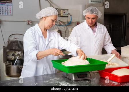 Bäcker wiegen den Teig auf der Waage Stockfoto