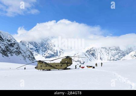 Talkeetna, Alaska, USA. 27. April 2022. Soldaten und Mitarbeiter des National Park Service entladen Ausrüstung und Zubehör aus einem CH-47 Chinook Hubschrauber auf dem Kahiltna Gletscher 27. April 2022. Die Zuckerbären der B Company, 1. Bataillon, 52. Aviation Regiment fliegen jedes Frühjahr aus Talkeetna, Alaska, um die NPS beim Aufbau eines Basislagers für Bergsteiger zu unterstützen, die versuchen, Denali zu besteigen. Kredit: U.S. Army/ZUMA Press Wire Service/ZUMAPRESS.com/Alamy Live Nachrichten Stockfoto