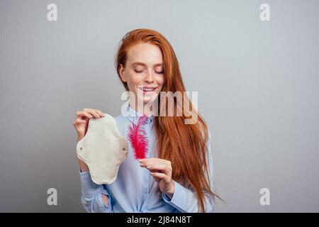 Rothaarige Ingwer lange Haare Frau hält umweltfreundliche Bio-Dichtungen aus Bio-Baumwolle und Einweg-Tampon.Wahl treffen Stockfoto