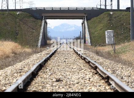 Bahngleise, die durch eine Brücke mit einem Berg im Hintergrund führen. Konzeptkunst Stockfoto