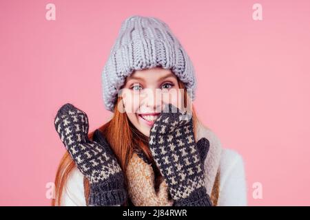 Rothaarige Ingwer Frau trägt stilvolle Hut, gestrickte Fäustlinge und Pullover in Studio rosa Hintergrund Stockfoto