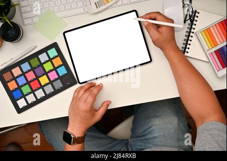 Grafikdesigner Arbeitsplatzkonzept, männlicher Grafikdesigner oder Bildredakteur mit digitalem Tablet am Schreibtisch. Farbprüfer, Schreibwaren und Stuf Stockfoto