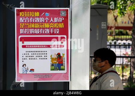 PEKING, CHINA - 13. MAI 2022 - Ein Bürger kommt am 13. Mai 2022 in Peking, China, An einem neuartigen Plakat zur Coronavirus-Impfung vorbei. Ab Mai 13, be Stockfoto