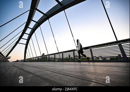 Berlin, Deutschland. 13.. Mai 2022. Ein Jogger läuft über eine Brücke im Stadtteil Berlin-Prenzlauer Berg. Quelle: Fabian Sommer/dpa/Alamy Live News Stockfoto