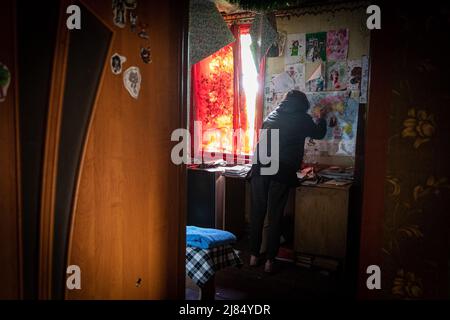 Slatyne, Ukraine. 5.. Mai 2022. Alina (12) macht ihre Hausaufgaben in ihrem Zimmer, da ihr Haus durch russische Schüsse beschädigt wurde und sie jetzt bei ihrer Mutter ohne Wasser- und Stromversorgung lebt. Während Russland seine Truppen wieder ausliefert und die Offensive auf den östlichen Teil der Ukraine konzentriert, sind Charkow und die umliegenden Gebiete in der Ukraine nun ständig von russischen Bombardierungen und Luftangriffen bedroht. (Bild: © Alex Chan Tsz Yuk/SOPA Images via ZUMA Press Wire) Stockfoto