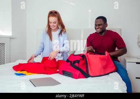 Porträt eines jungen Paares mit Pässen, Gepäck und Tickets, die Kleidung verpacken Stockfoto