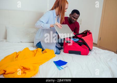 Porträt eines jungen Paares mit Pässen, Gepäck und Tickets, die Kleidung verpacken Stockfoto