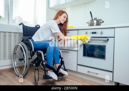 Junge rothaarige Ingwer behinderte Frau im Rollstuhl tragen gelbe Ribon Handschuhe und Reinigung Wohnung Stockfoto