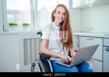 Rothaarige Ingwerfrau im Rollstuhl in der Küche Stockfoto